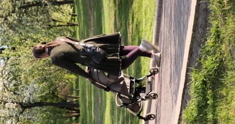 Vertical video mom pushing a stroller toddler rides a motorcycle shaped run bike Stock Footage 241206003