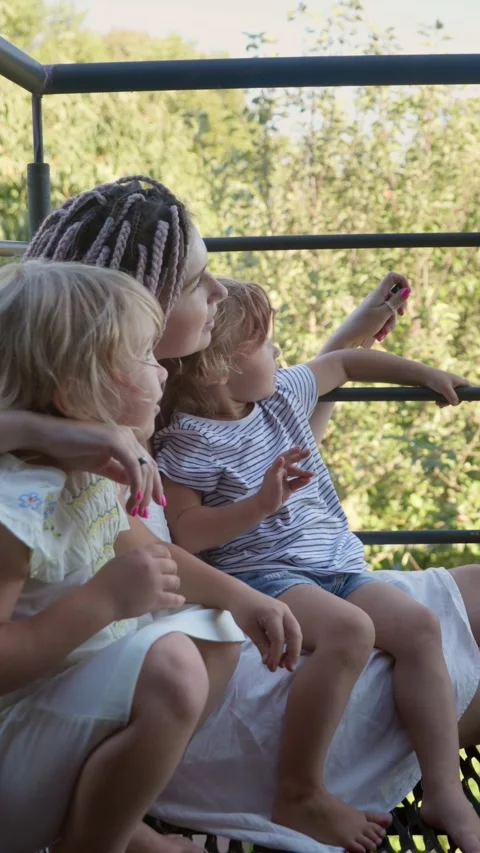 Vertical video. A mother and two daughters are sitting on the balcony near the Video stock 283628993