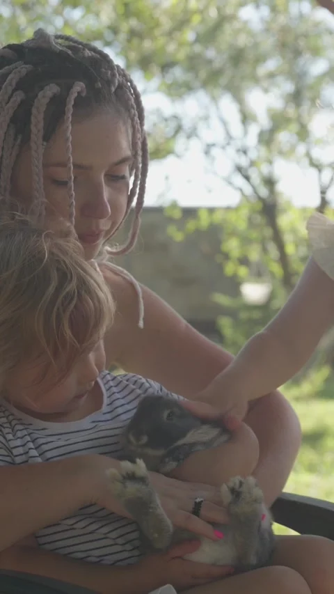 Vertical video. A mother with two daughters, a rabbit and a dog. Family Stock Footage 283628761