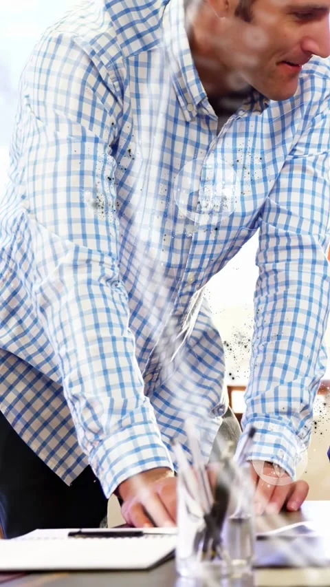 Vertical video: Moving man in blue shirt leaning over office table, pointing, Stock Footage 333020745