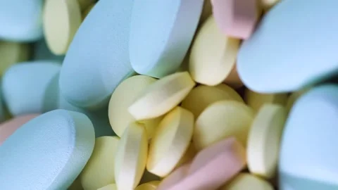 Vertical video Multi-colored yellow blue and pink pills lie on a table rotate Video stock 151989911