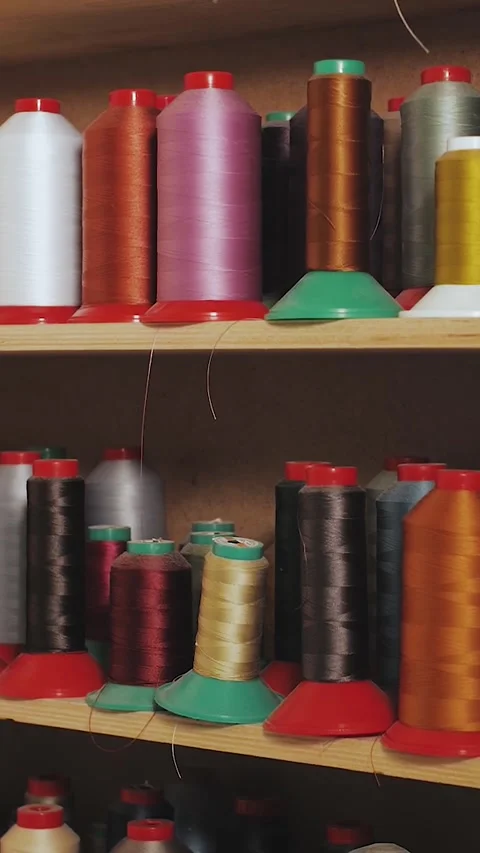 Vertical video. Multicolored spools of thread stand on shelves in a shoemakers Stock Footage 323451510