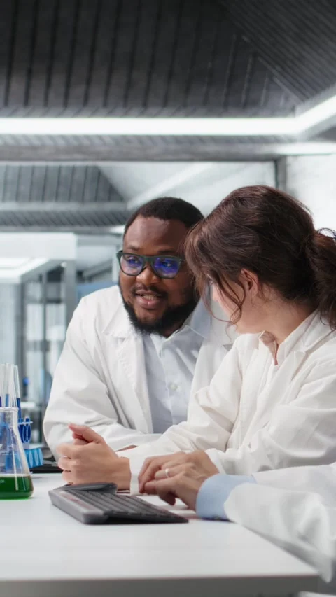 Vertical video Multiracial lab technicians at PC desk looking at 3D molecular Stock Footage 319505910