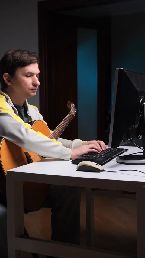 Vertical video Musician composing music on computer with guitar nearby Stock-Footage 308967904