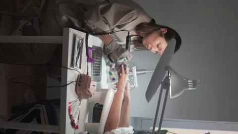 Vertical video of a nail technician performing an e-file manicure in a beauty Stock Footage 311871873