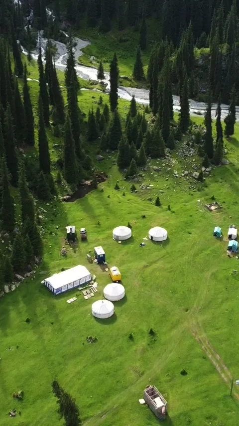 Vertical video: Nomad Yurt Camp and Tents in Lush Mountain Valley Aerial Video stock 332221685