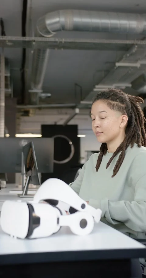 Vertical video: Non-binary African-American spotting VR headset at desk, Stock Footage 344695604