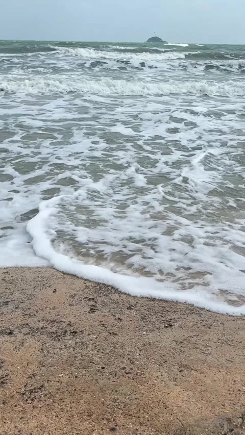 Vertical video of ocean waves rolling onto sandy beach with soft foam Stock Footage 325417576