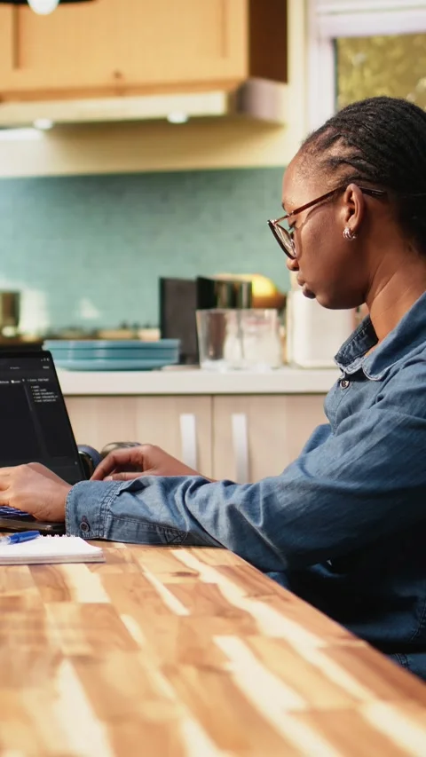 Vertical Video One person coding on laptop in kitchen representing remote work Stock Footage 344529614