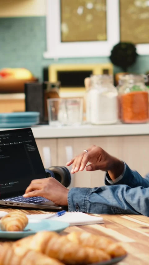 Vertical Video One person coding on laptop in kitchen representing remote work Stock Footage 344530862