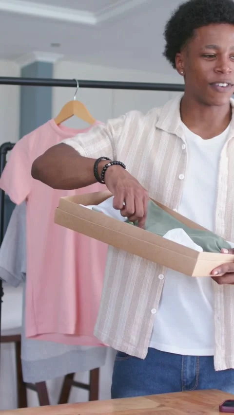 Vertical video: Opening box man revealing teal garment at home, rotating box, Stock Footage 348369708