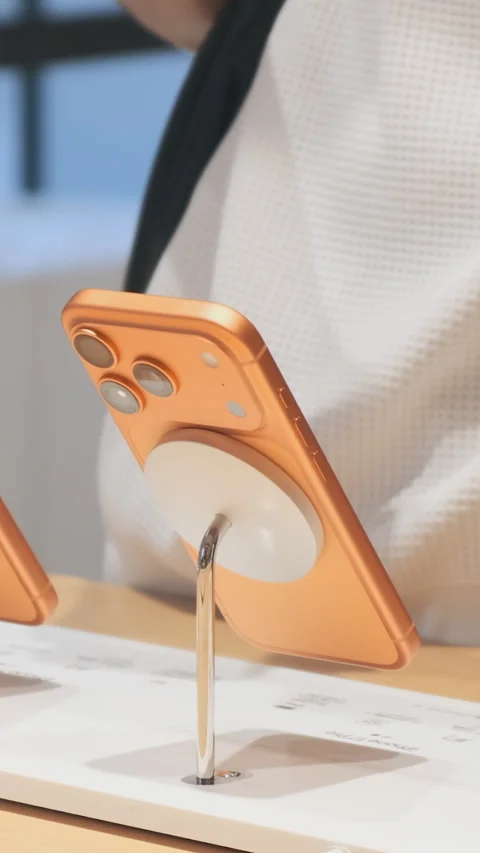 Vertical video: Orange iPhone 17 Pro smartphone on display in Apple Store Stock Footage 322514565