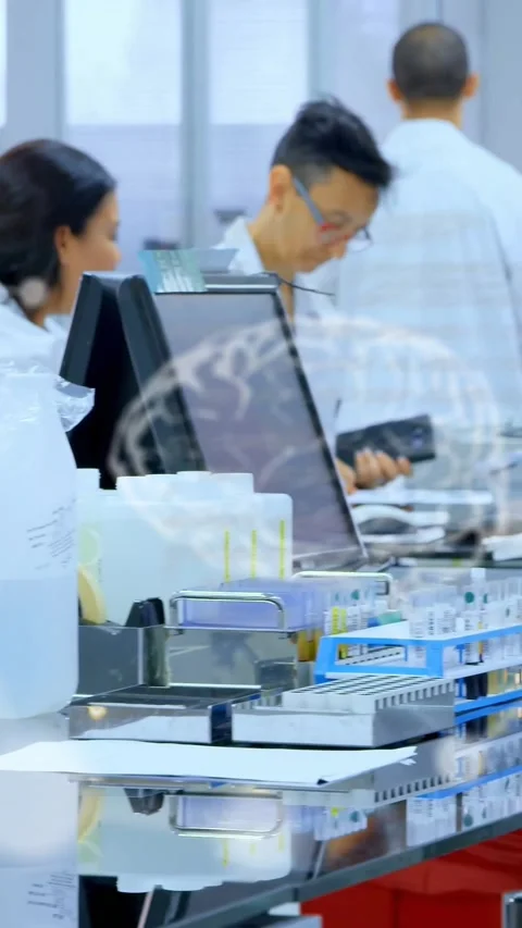 Vertical video: Overlays tagging lab bench, woman tech leaning, testing tubes as Stock Footage 330655717