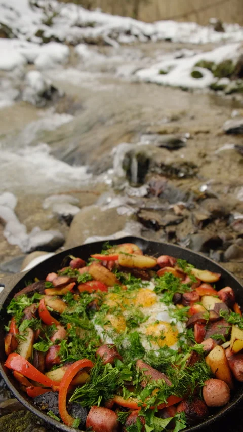 Vertical video of pan with appetizing potatoes and vegetables fried near river Stock Footage 297961913