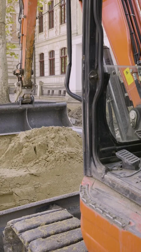 Vertical video of parked mini excavator on sand pile at urban construction site Stock Footage 345412241
