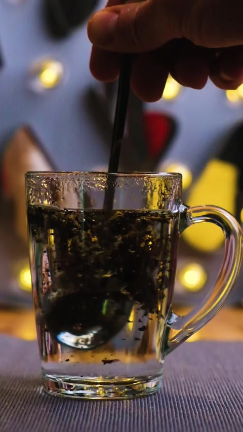Vertical video particles of black tea are poured into a glass transparent mug Stock Footage 149917658