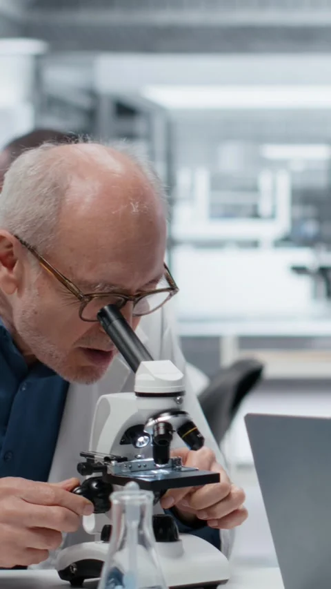 Vertical video Pathologist examining biopsy slide while coworker documents Stock Footage 326555313