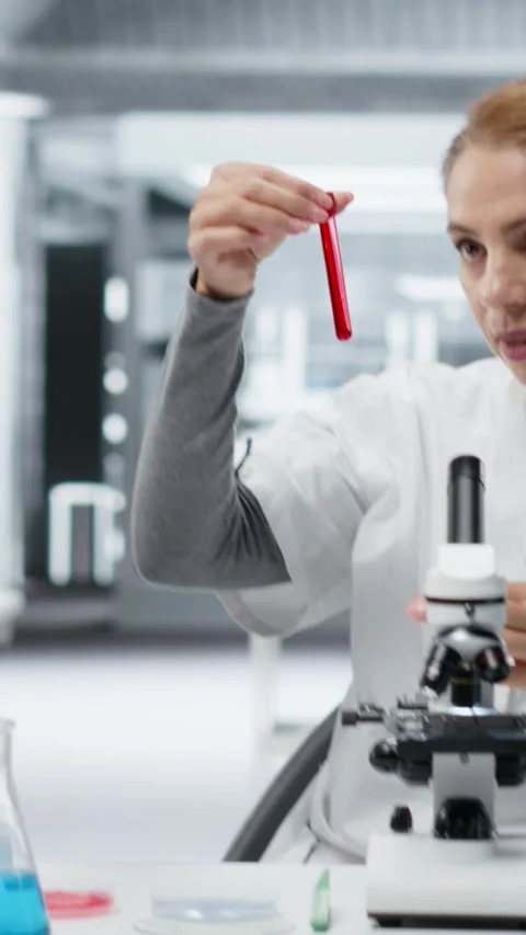 Vertical video Pathologist examining biopsy slide while colleague documents Stock Footage 327098444