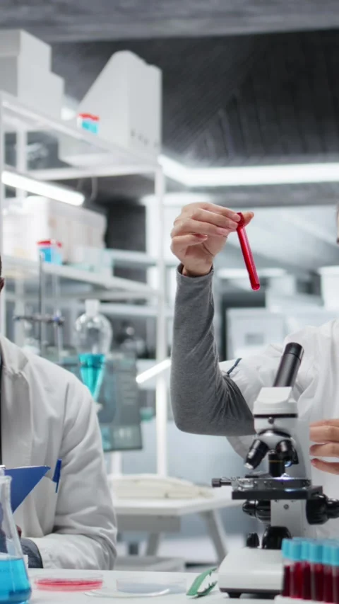 Vertical video Pathologist examining biopsy slide while colleague documents Stock Footage 327243805