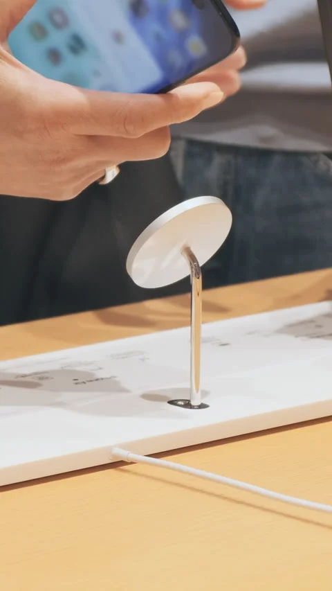Vertical video: People testing new iPhone 17 phones in Apple store stand. Custom Stock Footage 322515353