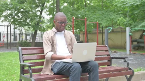 Vertical Video, Perplexed African Man Using Laptop Outdoor on Bench Video stock 310833865