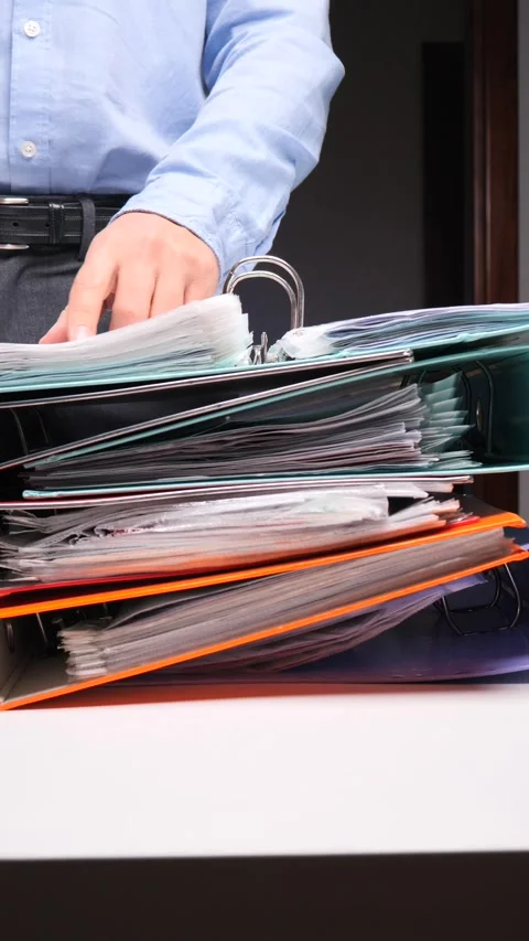 Vertical video Person looking through stack of overflowing office binders Stock Footage 322912620