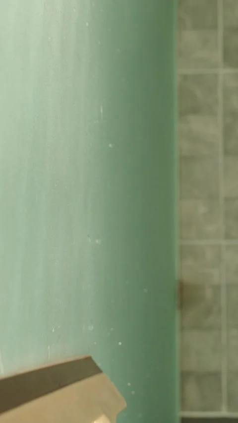 Vertical video. Person Using Squeegee on Steamy Glass Surface to Remove Moisture Stock Footage 315181369