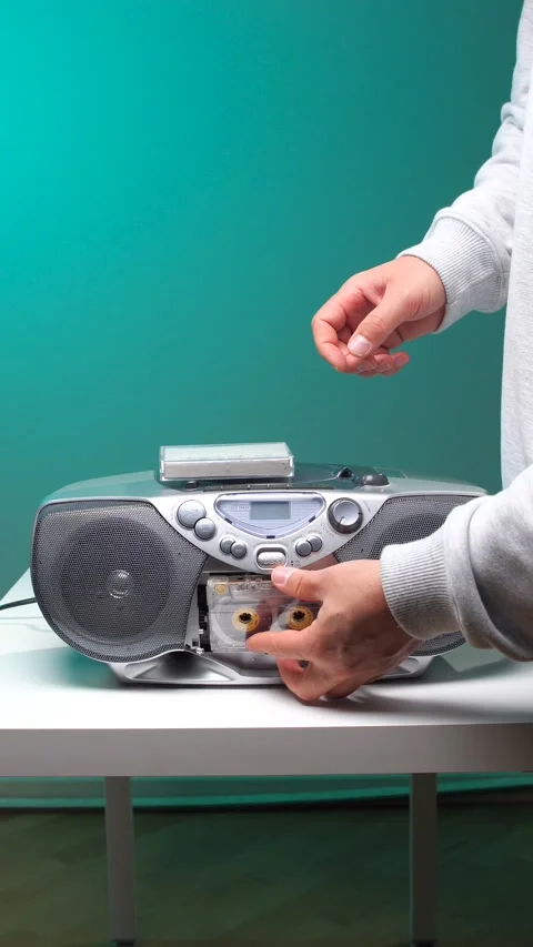 Vertical video person's hand pressing a button on a silver retro boombox with a Stock Footage 345530075