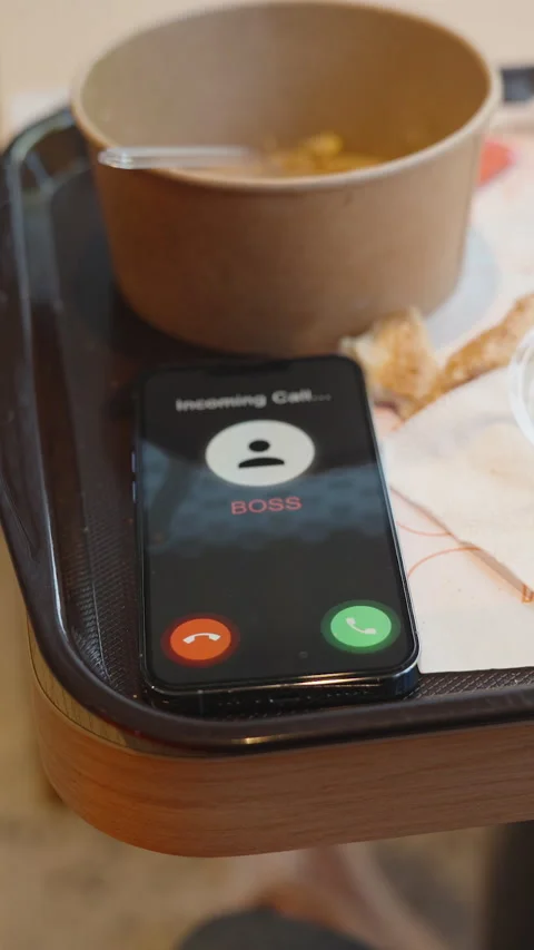 Vertical video. Phone Displaying Incoming Boss Call on Fast Food Tray with Stock Footage 305483624