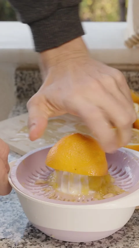 Vertical video. A pile of oranges on the table, a man manually squeezing fresh j Stock Footage 262022591
