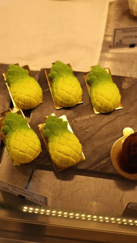 Vertical video: Pineapple-shaped desserts with a velvety finish are displayed on Stock Footage 300784053