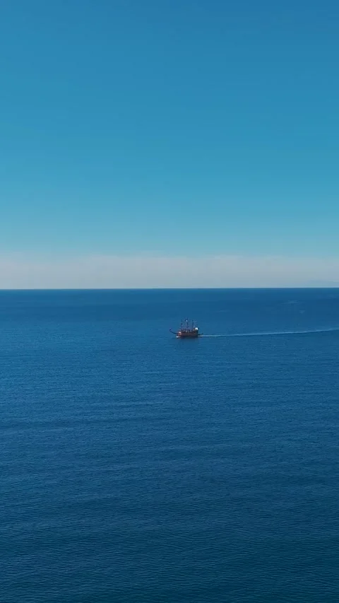 Vertical Video: Pirate Ship Sailing in the Open Sea With Blue Water and Bright Stock Footage 300338375