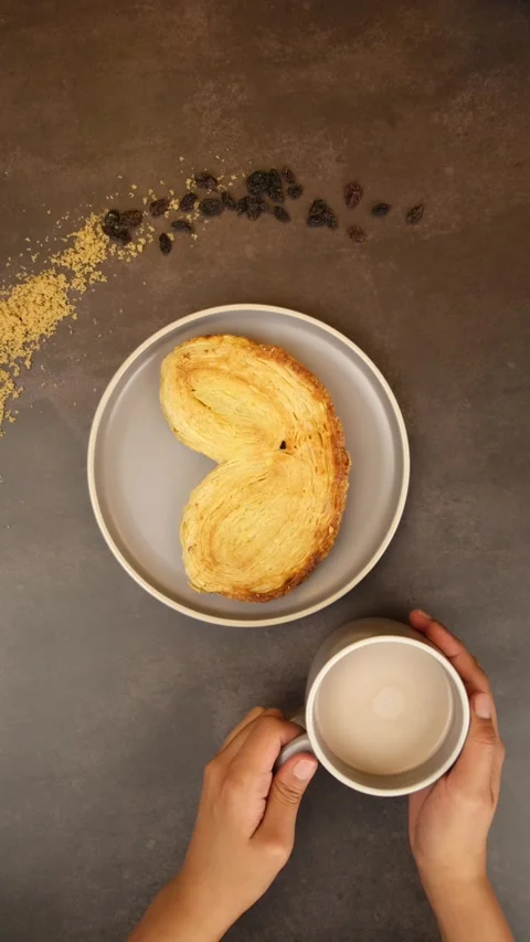 Vertical video Placing a cup of creamy latte next to a plate of Palmier bread Stock Footage 279354887