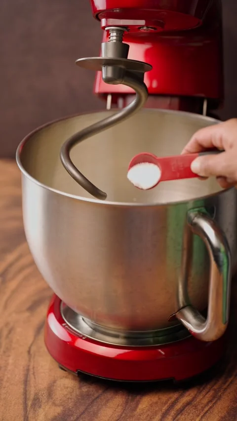 Vertical video, planetary mixer, adding a teaspoon of salt with a red spoon Stock Footage 282499694
