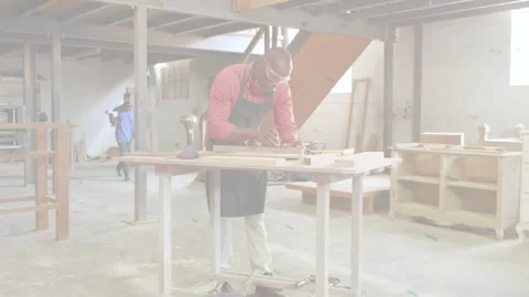 Vertical video: Planing woodworker in red apron using plane at shop bench, crew Video stock 334112802