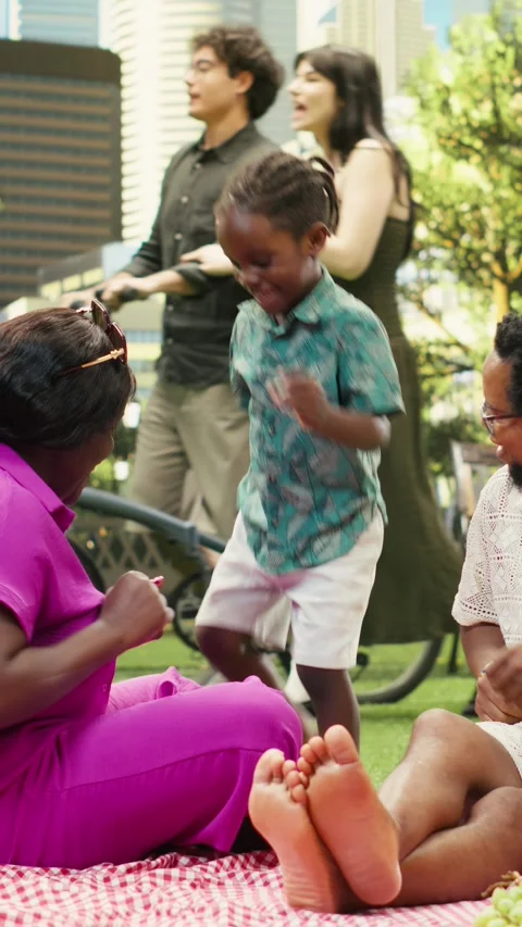 Vertical Video Playful boy doing funny dance moves with parents during picnic Stock Footage 341471606