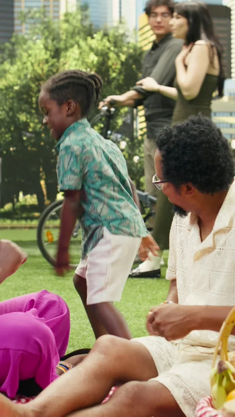 Vertical Video Playful boy doing funny dance moves with parents during picnic Stock Footage 341473079