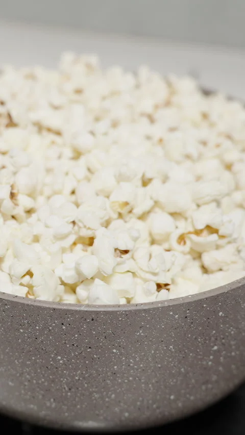 Vertical video. Popcorn explodes at the bottom of the pot and tosses up the alre Stock Footage 270385766