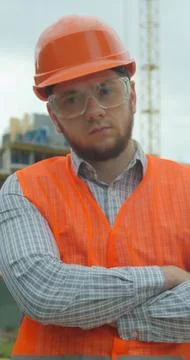Vertical video. Portrait of an architect or builder in hard hat standing in f Stock Photos
