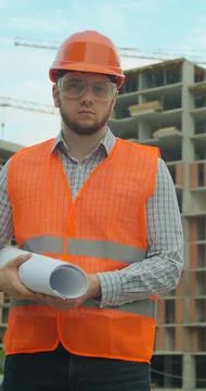 Vertical video. Portrait of an architect or builder in hard hat standing in f Stock Photos