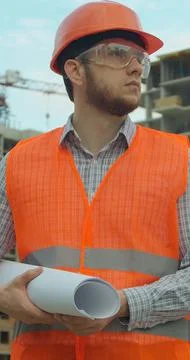 Vertical video. Portrait of an architect or builder in hard hat standing in f Stock Photos