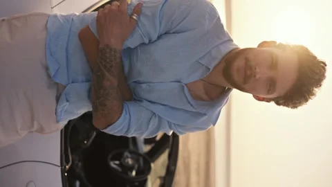 Vertical video: Portrait of a bearded man in a blue shirt stands with his arms 스톡 동영상 250240850