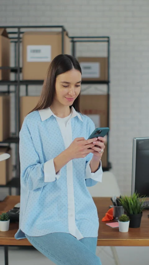 Vertical video. Portrait of a woman using a smartphone at work in a warehouse Stock Footage 345731592