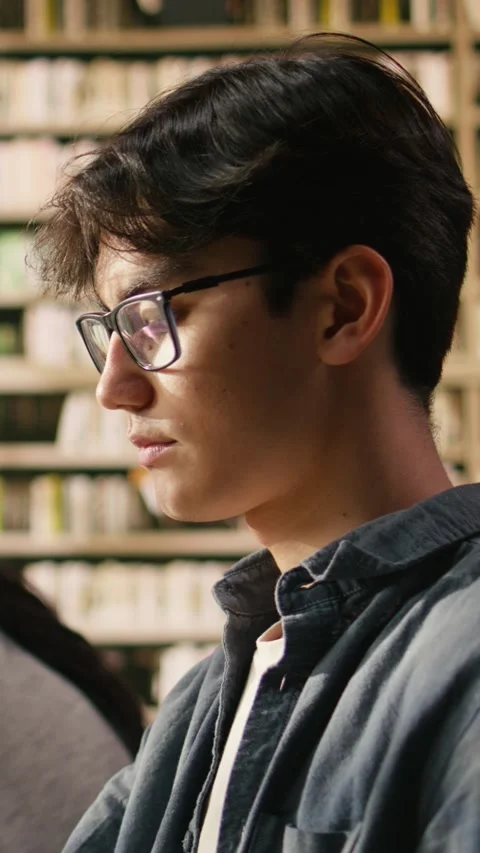 Vertical Video Portrait of young man reading open book at library study table Stock Footage 336379460