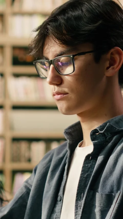 Vertical Video Portrait of young man reading open book at library study table Stock Footage 336380513