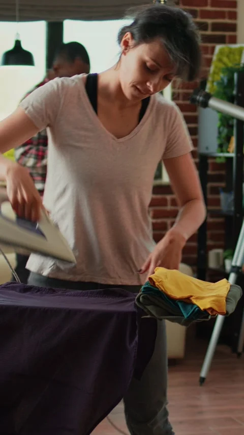 Vertical video: Positive person singing and having fun ironing clothes in living Stock-Footage 229455885