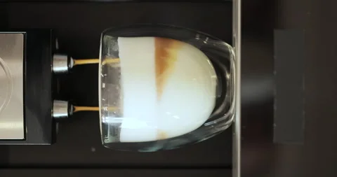 Vertical video of pouring cappuccino from automatic coffee machine in glass cup Stock Footage 252756426