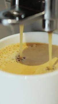 Vertical video. Pouring coffee stream into cup. Home making hot Espresso. Flo Фото