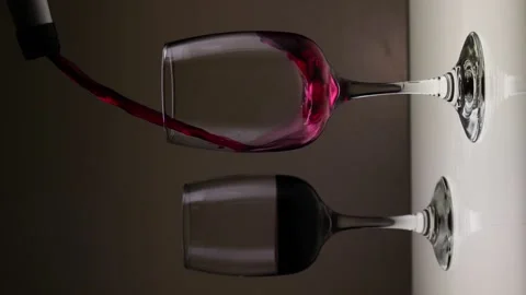 Vertical video. Pouring red wine into a glass on a dark background. Stock Footage 146640516