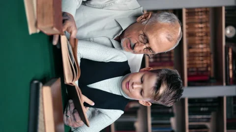 VERTICAL VIDEO POV caring 70s grandfather and smiling male grandchild reading Stock Footage 165036026